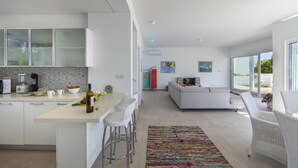 A modern kitchen with a central island, bar stools, and a dining area with a sofa and chairs. - The Ultimate Guide to Renting Your Luxury 3 Bedroom Villa Minutes From the Beach, Protaras Villa 1530 (Paralimni)