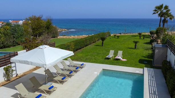A pool area with lounge chairs and a view of the ocean. - 5 Star Beachfront Villa, Protaras Villa 1536 (Paralimni)