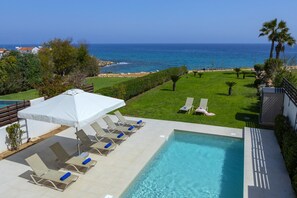 A pool area with lounge chairs and a view of the ocean. - 5 Star Beachfront Villa, Protaras Villa 1536 (Paralimni)