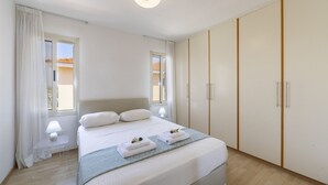 A bedroom with a bed, bedside lamps, a bedside table, a window, and a wardrobe. - 5 Star Beachfront Villa, Protaras Villa 1536 (Paralimni)