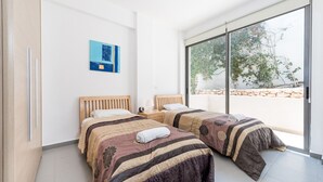 Ein modernes Schlafzimmer mit zwei Betten, einem Nachttisch, einer Lampe und einem Gemälde an der Wand.