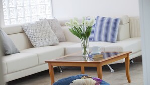 A modern living room with a glass coffee table, a white sofa with patterned cushions, a blue bean bag, and a vase with white flowers. - Imagine Your Family Renting This Luxury Villa With Large Private Pool, Protaras Villa 1543 (Paralimni)