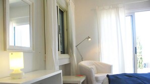 A bedroom with a bed, a bedside table with a lamp, a chair, a desk, and a window with curtains. - How to Rent Your Own Villa in Paphos With Fantastic Private Pool, Paphos Villa 1418 (Neo Chorio)
