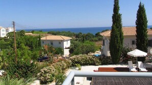 A residential area with a view of the sea, a swimming pool, and a white building with a tiled roof. - How to Rent Your Own Villa in Paphos With Fantastic Private Pool, Paphos Villa 1418 (Neo Chorio)