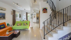 A spacious living area with a staircase, a dining area, and a kitchen visible through an archway. - Imagine You and Your Family Renting This Luxury Villa Minutes From the Beach, Protaras Villa 1501 (Paralimni)