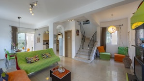 A spacious living area with a green sofa, a coffee table, and a staircase leading to an upper floor. - Imagine You and Your Family Renting This Luxury Villa Minutes From the Beach, Protaras Villa 1501 (Paralimni)