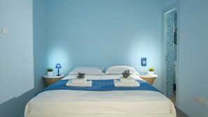 Une chambre à coucher avec un lit, deux tables de chevet, une lampe et une plante en pot.