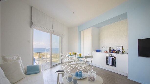 Un salon moderne avec balcon, un coin repas et une cuisine.