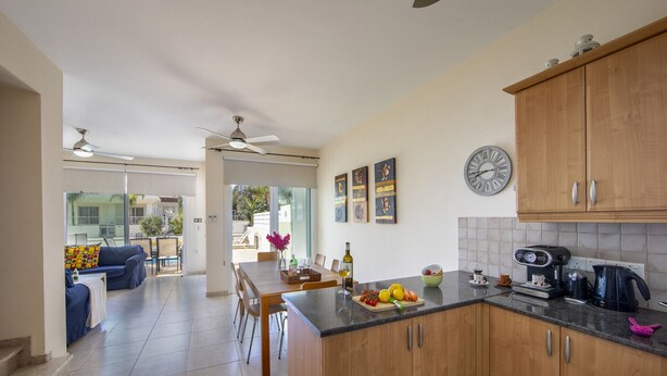 Una cocina moderna con armarios de madera, una cafetera y un comedor con mesa y sillas.