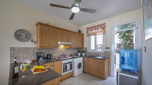 Una cocina con armarios de madera, horno empotrado, lavadora y dispensador de agua.