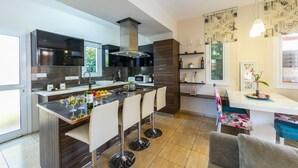 Eine moderne Küche mit einer zentralen Kochinsel, Barhocker und einem Essbereich mit einem Blumenstuhl.