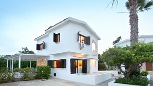 A modern two-story house with a covered patio area, a small garden, and a parking space. - The Ultimate Guide to Renting Your Luxury 3 Bedroom Villa Minutes From the Beach, Protaras Villa 1496 (Paralimni)