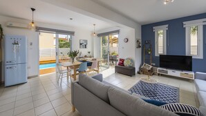 Ein geräumiger Wohnbereich mit Sofa, Fernseher und Esstisch.
