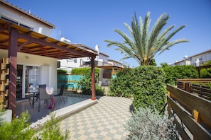 A patio with a checkered floor, outdoor furniture, a palm tree, and a wooden pergola. - Stunning Family Villa in Larnaca, 1387 (Pervolia)
