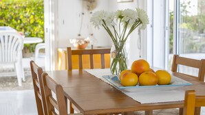 Ett matbord i trä med en vit bordsduk, en vas med vita blommor och en tallrik med apelsiner.