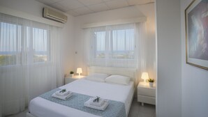 Ett hotellrum med en stor säng, två sängbord, en väggmonterad luftkonditioneringsanläggning och en tavla på väggen.
