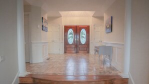 A hallway with a wooden staircase leading to a double door with glass panels. - Oceanfront / Sleeps 16 / Beach Days / Screen Porch (Isle of Palms)
