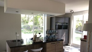 Una cocina moderna con una isla central, taburetes de bar, horno empotrado y un amplio ventanal con vistas al exterior.