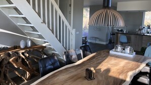 Un comedor moderno con una mesa de madera, sillas negras y una mesa baja de madera singular.