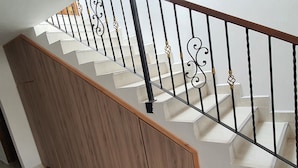 A wooden staircase with a black metal railing and a white wall. - Villa del Socorro (Jardín)