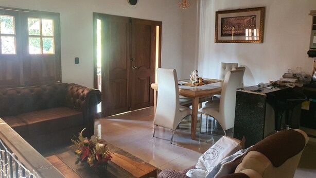 A living room with a wooden ceiling, a dining area with a table and chairs, a sofa, and a decorative plant on a glass table. - Villa del Socorro (Jardín)