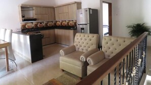 A kitchen with wooden cabinets, a refrigerator, and a dining area with a sofa. - Villa del Socorro (Jardín)