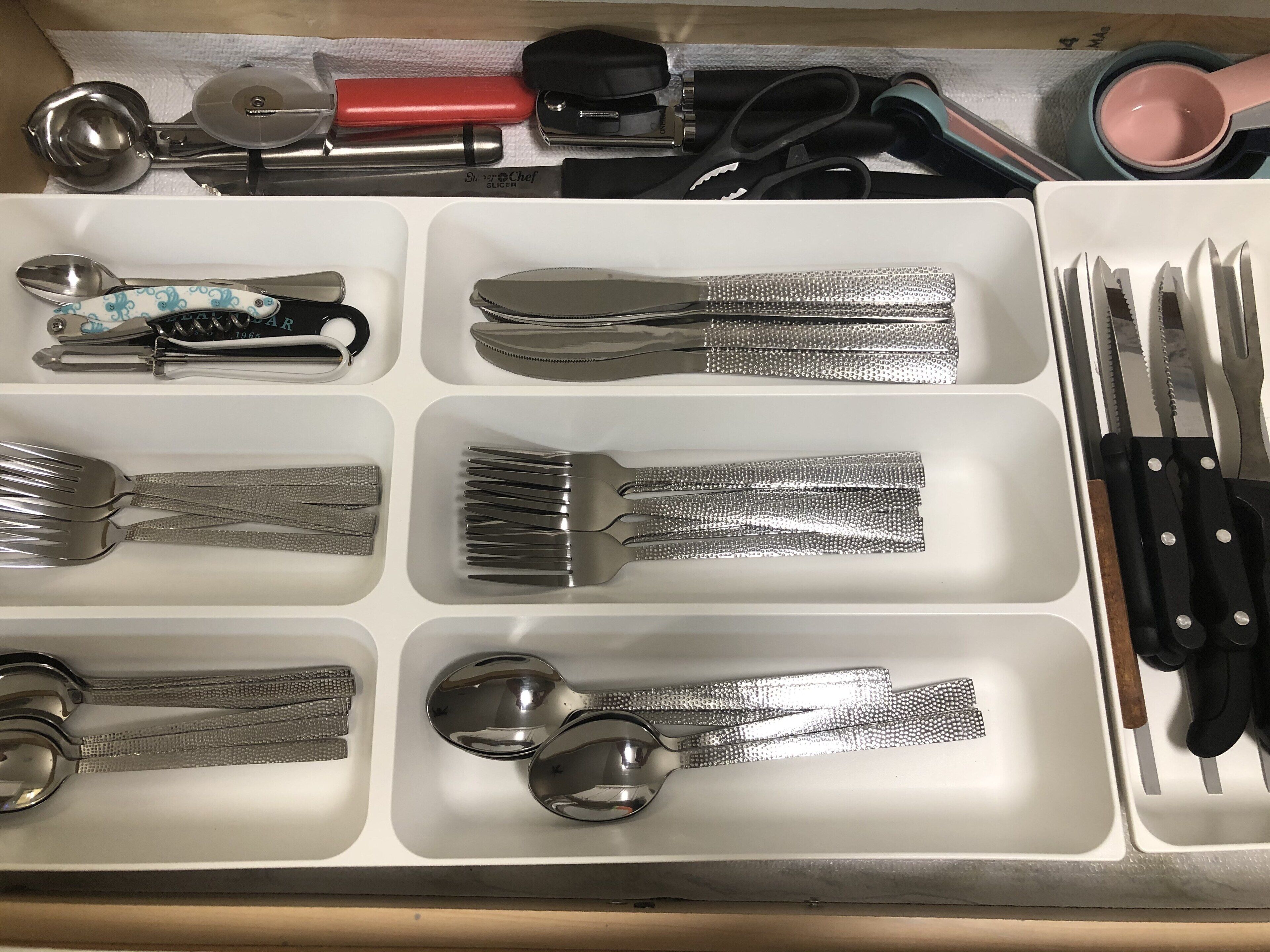 A drawer with various kitchen utensils, including spoons, forks, and knives, neatly organized in compartments.