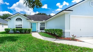 A single-story house with a front entrance, a garage, and a well-maintained lawn. - Centralized, stylish getaway. Short drive to beach, shopping, downtown, Mayo! (Jacksonville)