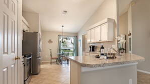 A kitchen with white cabinets, a granite countertop, and a dining area with a table and chairs. - Centralized, stylish getaway. Short drive to beach, shopping, downtown, Mayo! (Jacksonville)
