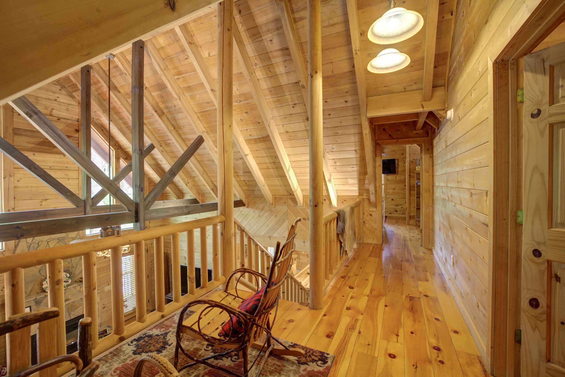 A wooden interior with a wooden staircase, a wooden railing, and a patterned rug.