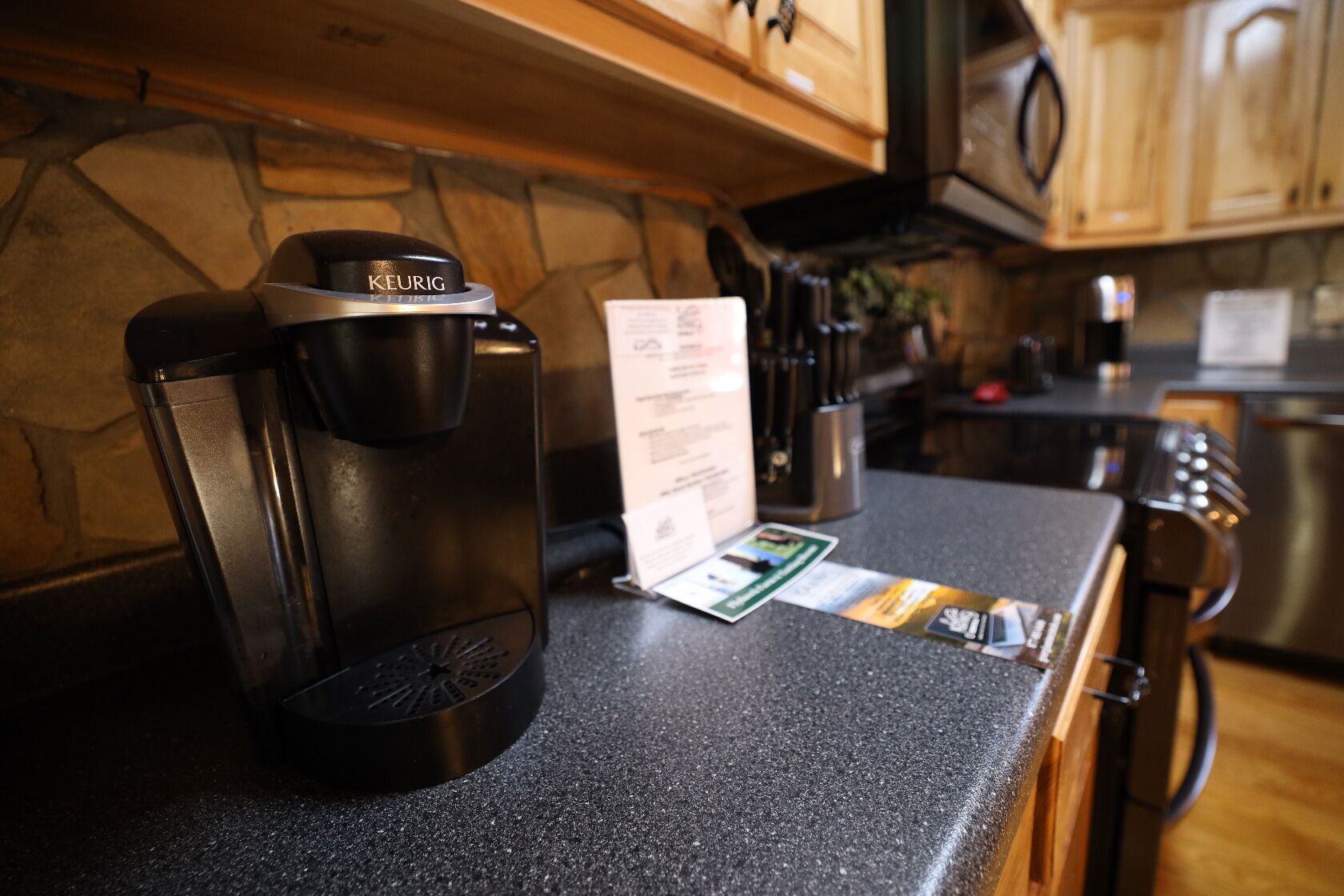 Una cafetera Keurig sobre una encimera de cocina con una tarjeta de menú y un juego de cartas.