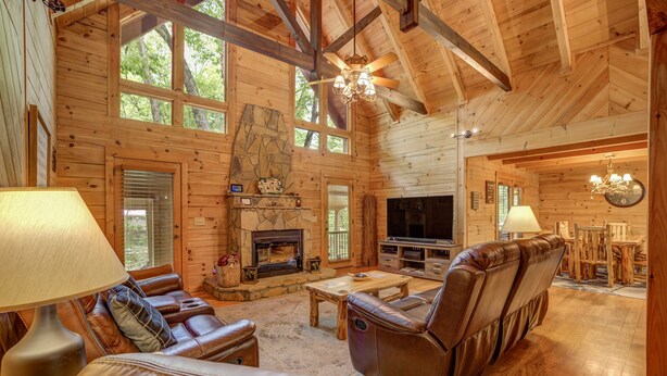 A spacious log cabin interior with a fireplace, leather seating, and a television. - River Haus - Riverfront Luxury Lodge in Downtown Helen (Helen)