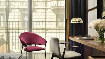 A room with a desk, two chairs, a lamp, and a vase with flowers.
