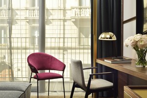 A room with a desk, two chairs, a lamp, and a vase with flowers.