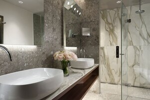Een moderne badkamer met een groot wit wastafel, een spiegel en een douche met glazen wanden.