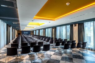 A conference room with rows of chairs, large windows, and a checkered floor.