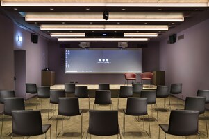 A conference room with a stage, a large screen, and multiple chairs arranged in rows.