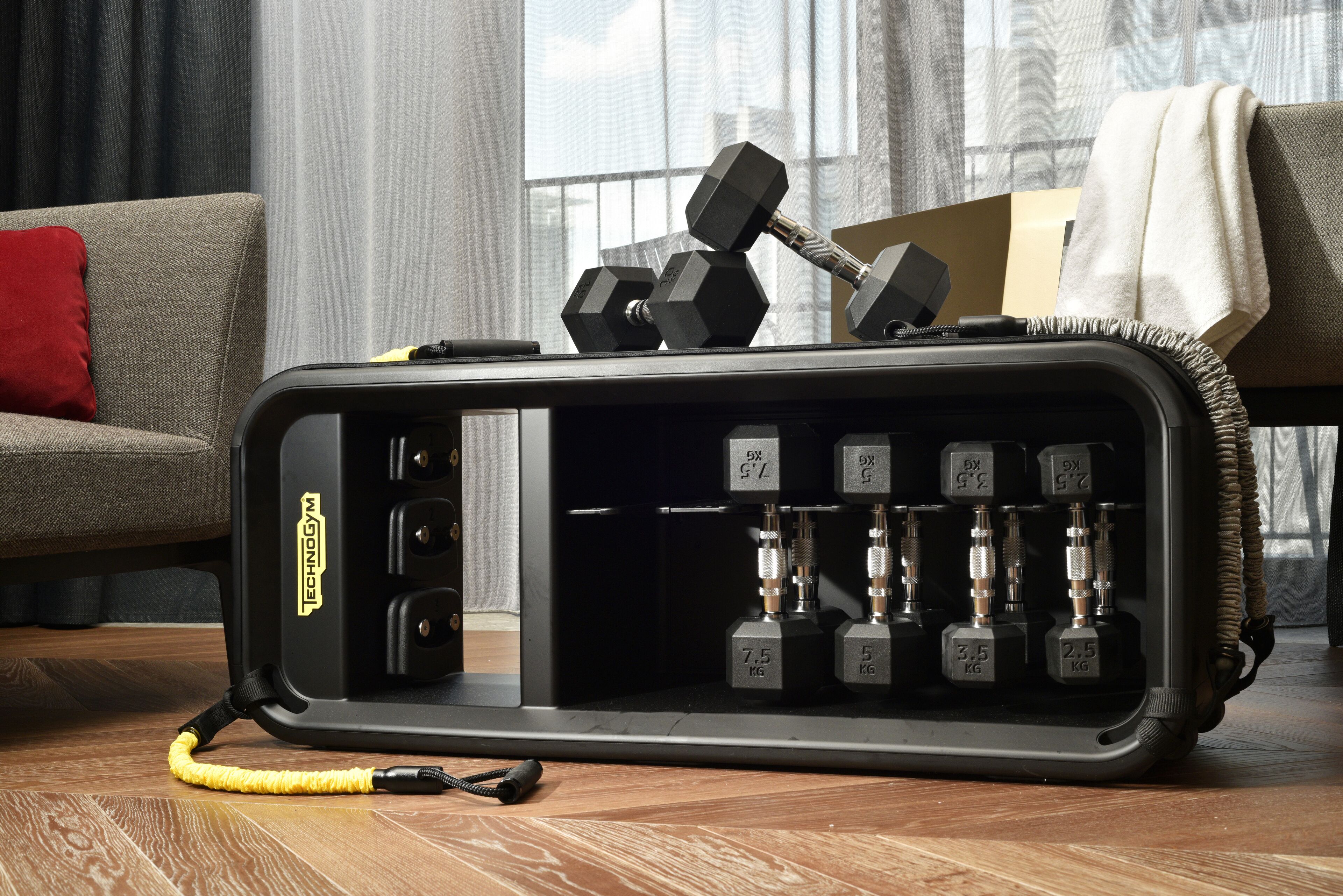 A home gym setup with adjustable dumbbells and a resistance band on a wooden floor.