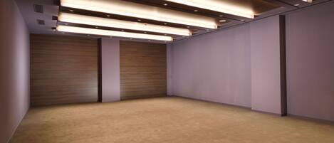 Una habitación amplia con piso alfombrado, paneles de madera y iluminación empotrada.