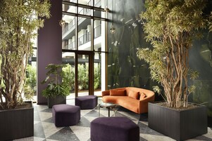 A modern lobby with a large window, a sofa, and several potted plants.
