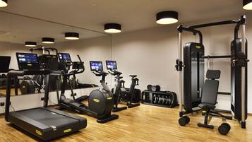 Une salle de sport équipée de tapis de course, de vélos d’appartement, d’une machine de musculation et d’haltères.