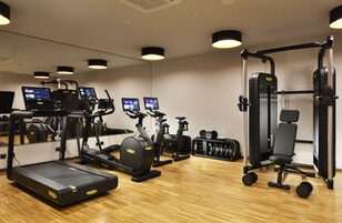 Une salle de sport équipée de tapis de course, de vélos d’appartement, d’une machine de musculation et d’haltères.