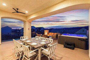An outdoor patio with a dining table set for six, surrounded by chairs, a hot tub, and a fireplace. - 5 Suites, Private Pool, 2 Hot Tubs for 19, 2 Fire Pits, 2 Fridges Sleeps 30 (Hurricane)