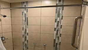 A shower area with a bathtub, tiled walls, and a glass shower door.