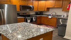 A kitchen with wooden cabinets, a stainless steel refrigerator, a microwave, an oven, and a sink.