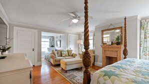 A bedroom with a four-poster bed, a wooden floor, a ceiling fan, a fireplace, and a large mirror. - "SABINO" 1 Bdrm Suite (Phippsburg)