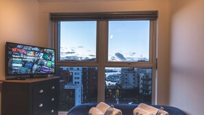 Ein Hotelzimmer mit einem Bett, einem Schminktisch und einem Fernseher, der Netflix-Inhalte zeigt.