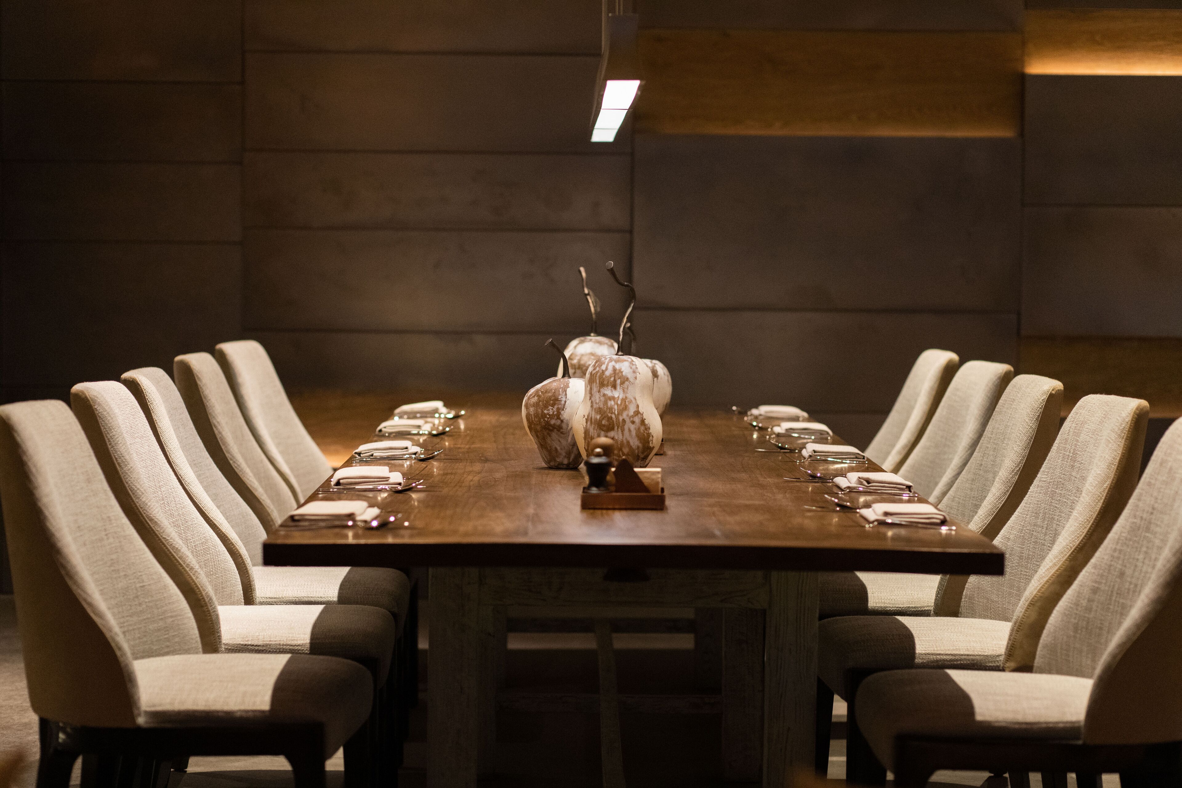 A long rectangular dining table with multiple chairs around it, set for a meal.