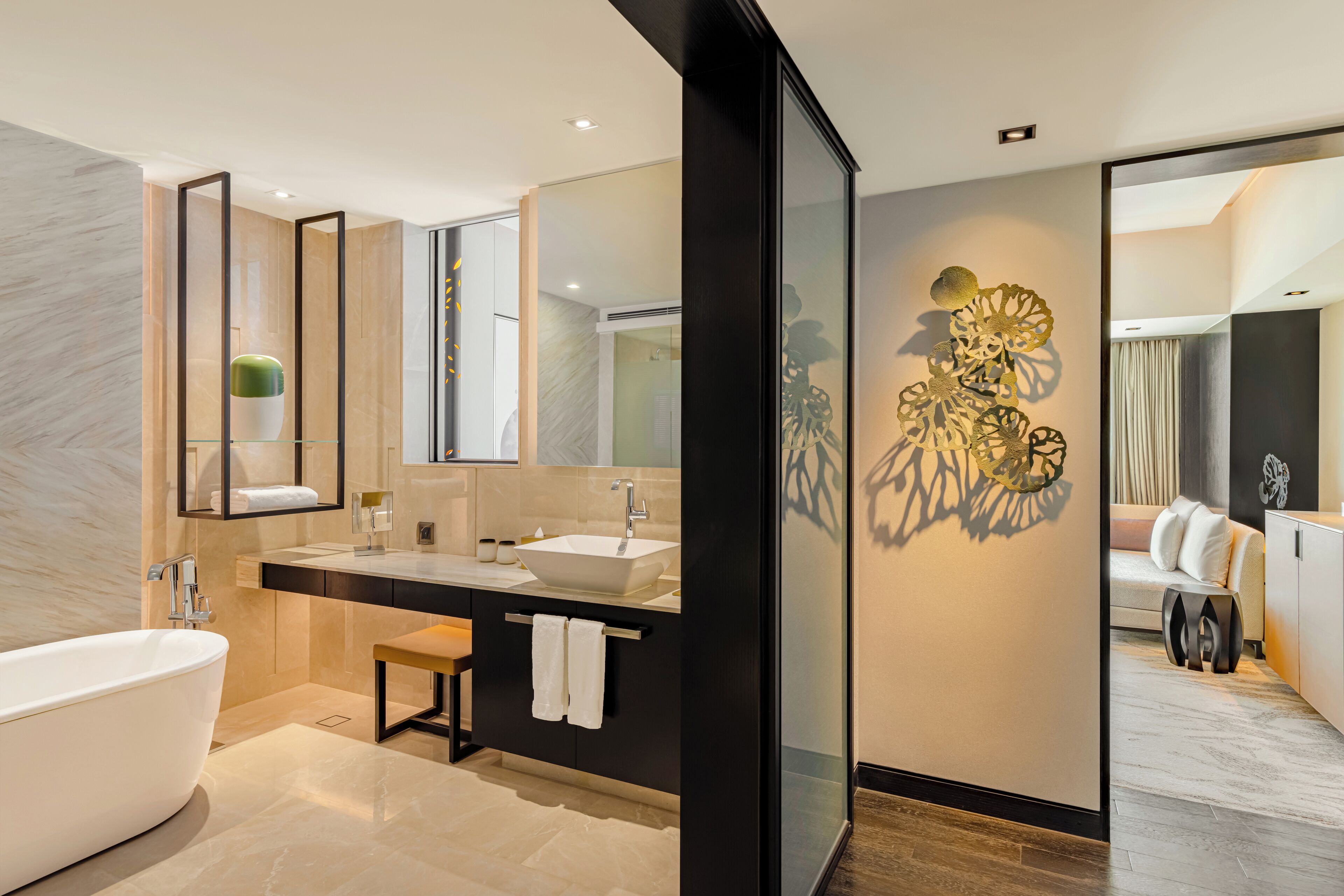 A modern bathroom with a freestanding bathtub, a double sink vanity, and a decorative wall piece.