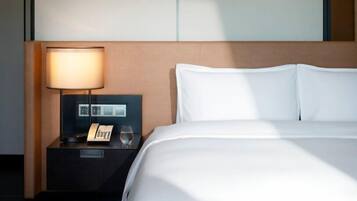 A hotel room with a large bed, a bedside table with a lamp, and a phone.